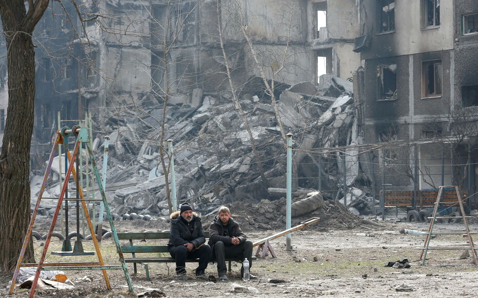 Local residents sit on a bench near an apartment building destroyed in the course of Ukraine-Russia conflict in the besieged southern port city of Mariupol, Ukraine March 25, 2022. REUTERS/Alexander Ermochenko TPX IMAGES OF THE DAY