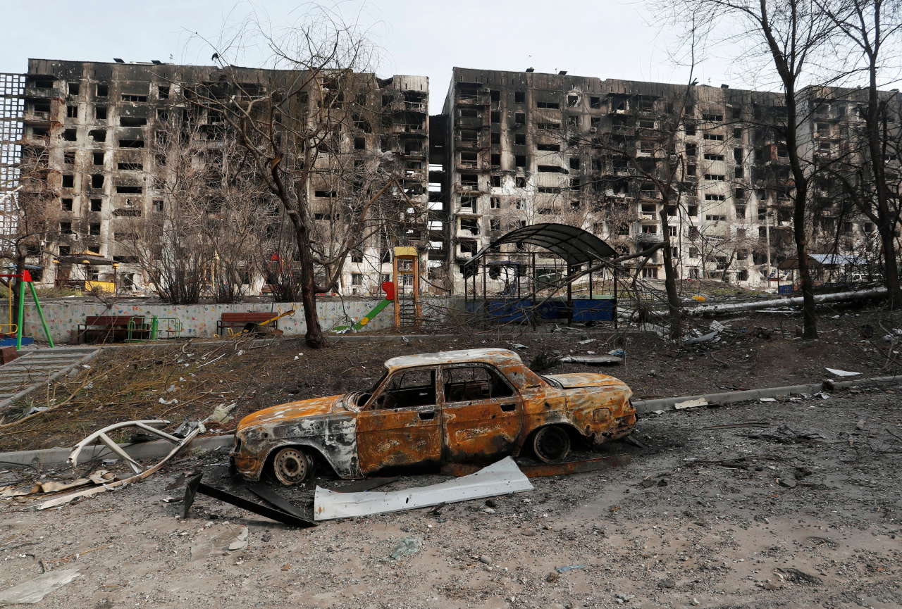 A charred car is seen in front of an apartment building destroyed during Ukraine-Russia conflict in the besieged southern port city of Mariupol, Ukraine March 30, 2022. REUTERS/Alexander Ermochenko