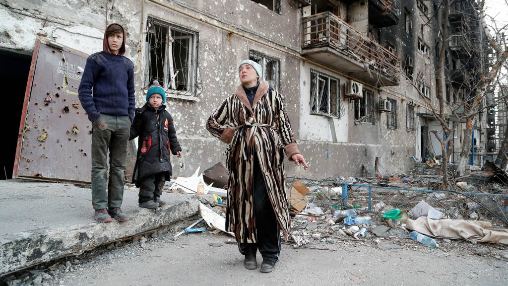 The Bykovets family members, Olga, 42, Ilya, 13, and Yegor, 5, who seek refuge in abandoned apartments of a residential building damaged in the course of Ukraine-Russia conflict, gather in a courtyard in the southern port city of Mariupol, Ukraine April 1, 2022. REUTERS/Alexander Ermochenko TPX IMAGES OF THE DAY